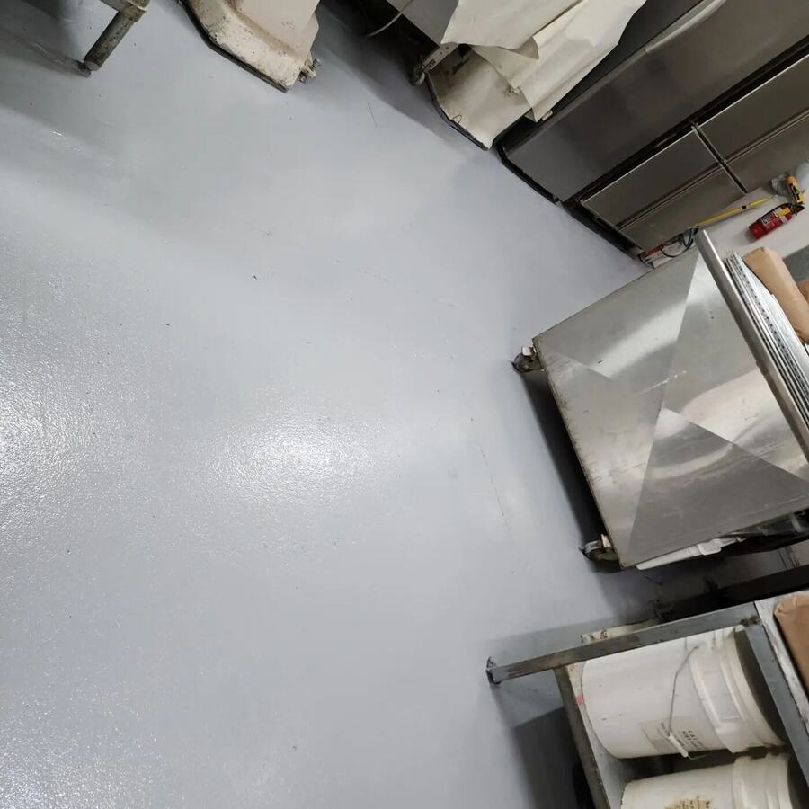 Grey epoxy floor in a commercial kitchen beside stainless steel equipment