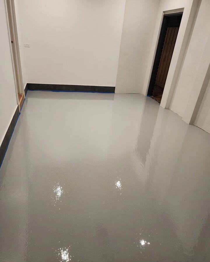 Grey epoxy floor with a black coved edge at the wall in an empty room