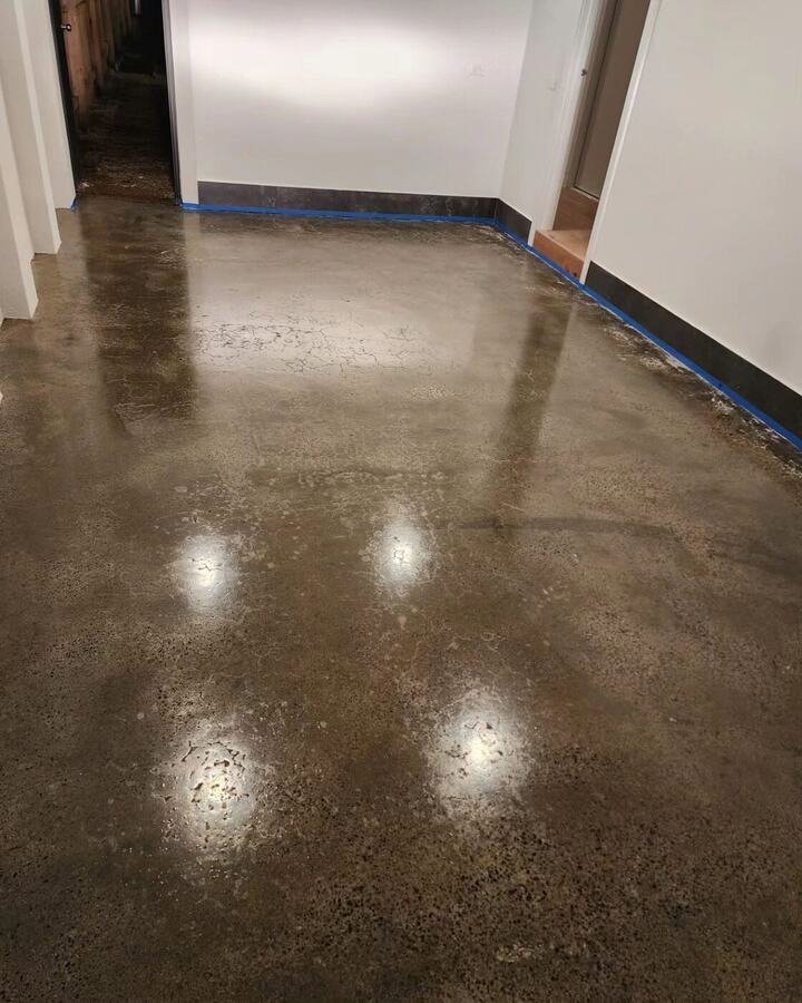 Glossy sealed concrete floor inside a commercial building with blue tape along the wall