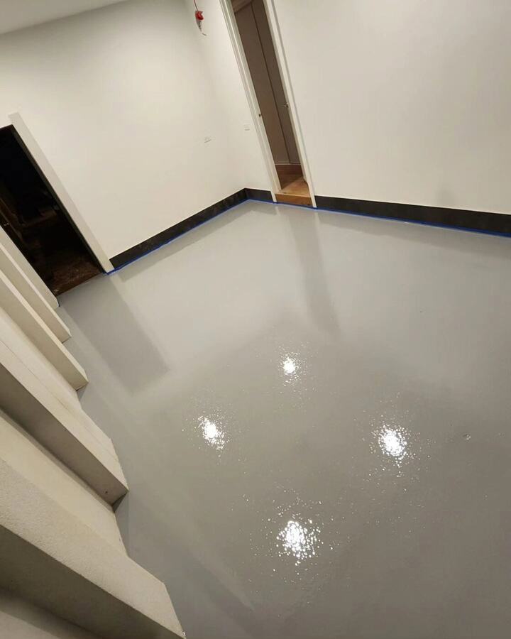 Glossy grey resin floor with a dark edge strip along the wall in an interior room