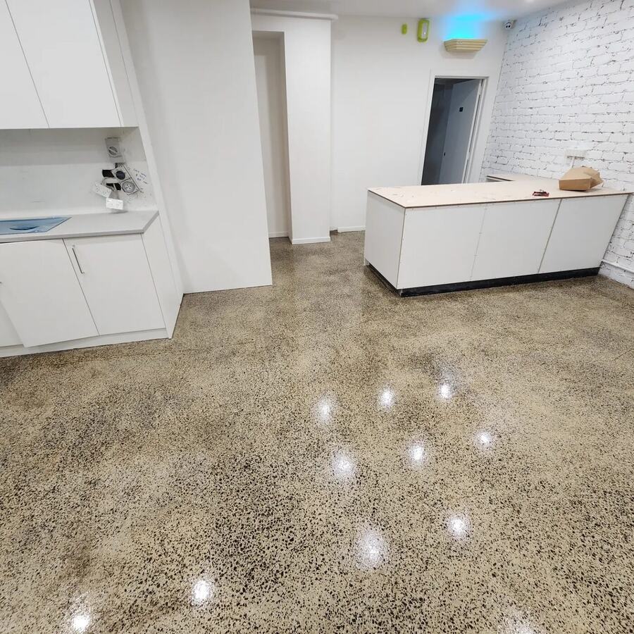 Polished concrete floor reflecting ceiling lights beside white joinery in a commercial space