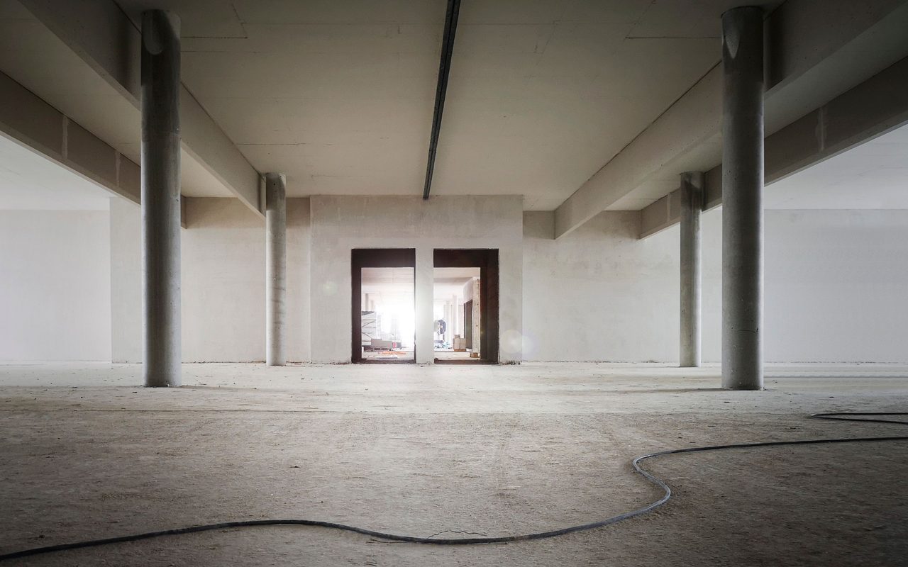 Bare unfinished concrete slab in an empty commercial space with a cable on the floor
