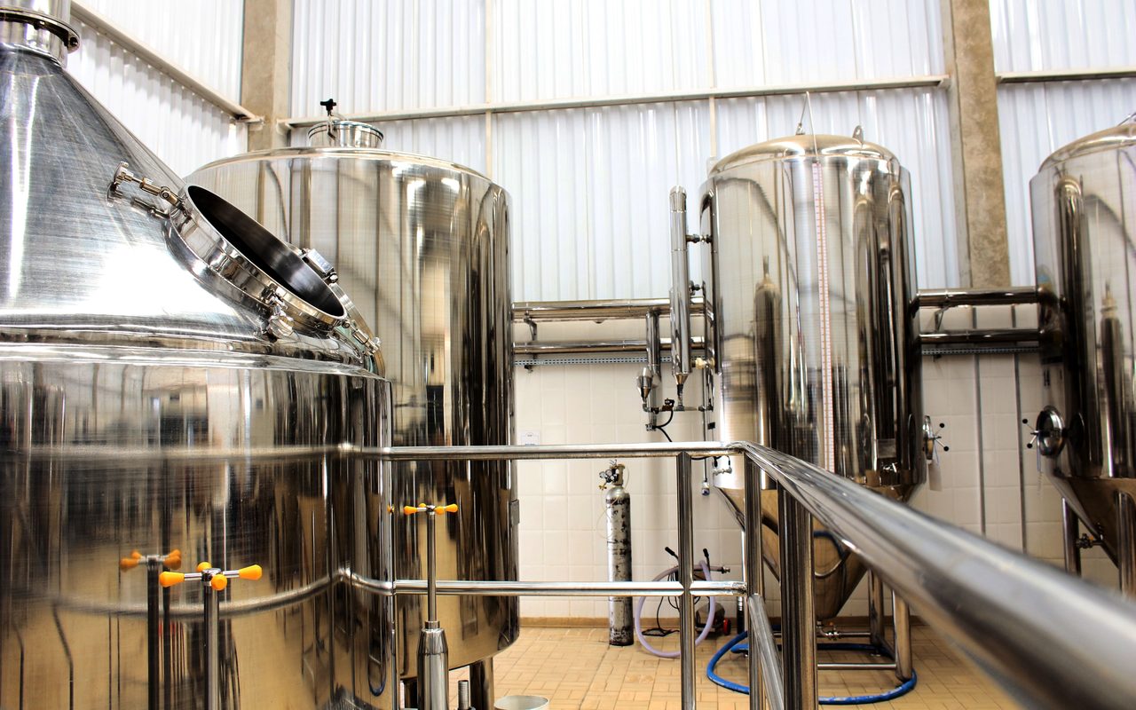 Stainless steel processing tanks on a tiled floor in a beverage production plant