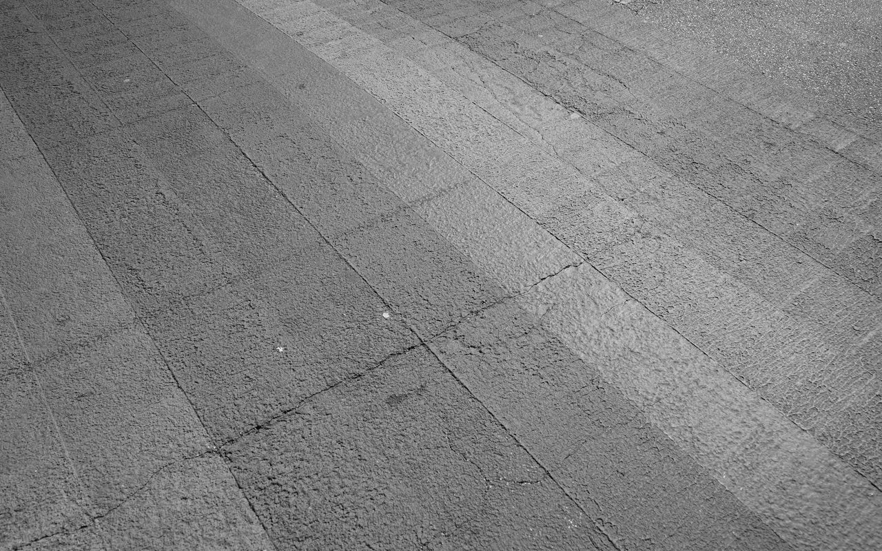 Grey concrete floor with joint lines and fine cracks running across it