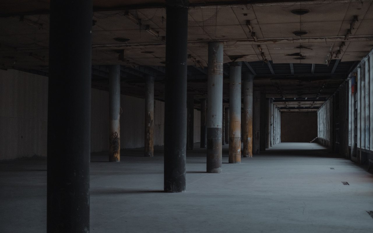 Empty industrial hall with columns and a bare concrete floor in low light