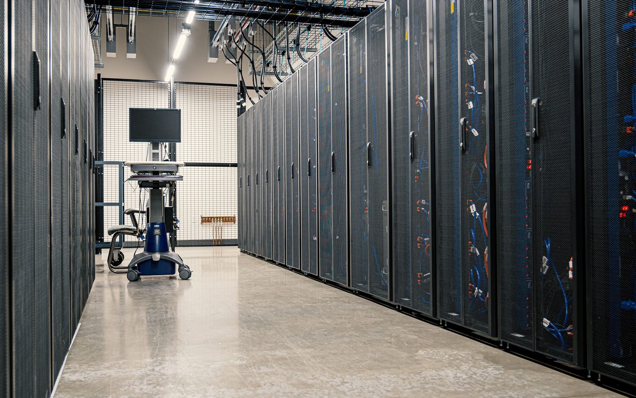 Server racks lining an aisle with a concrete floor in a data centre