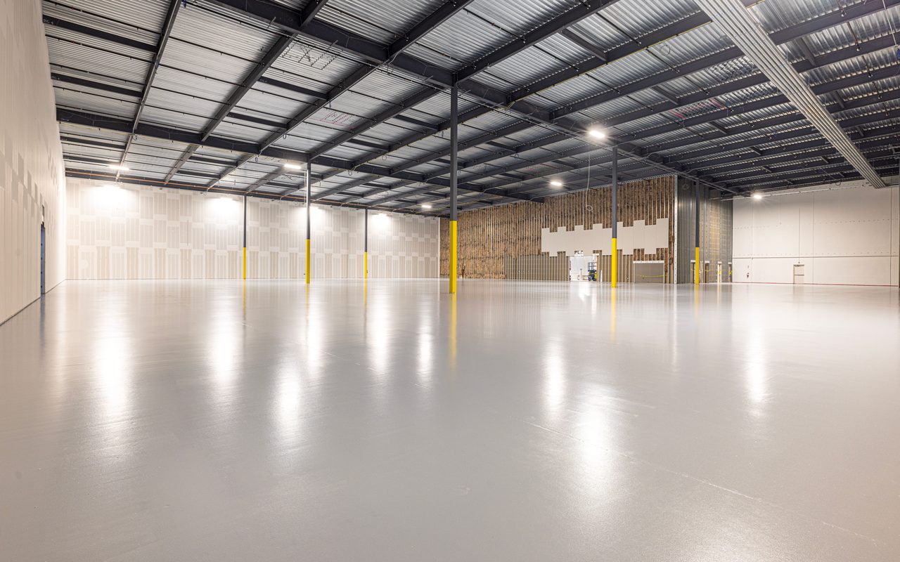 Empty warehouse interior with a smooth coated floor and yellow column guards