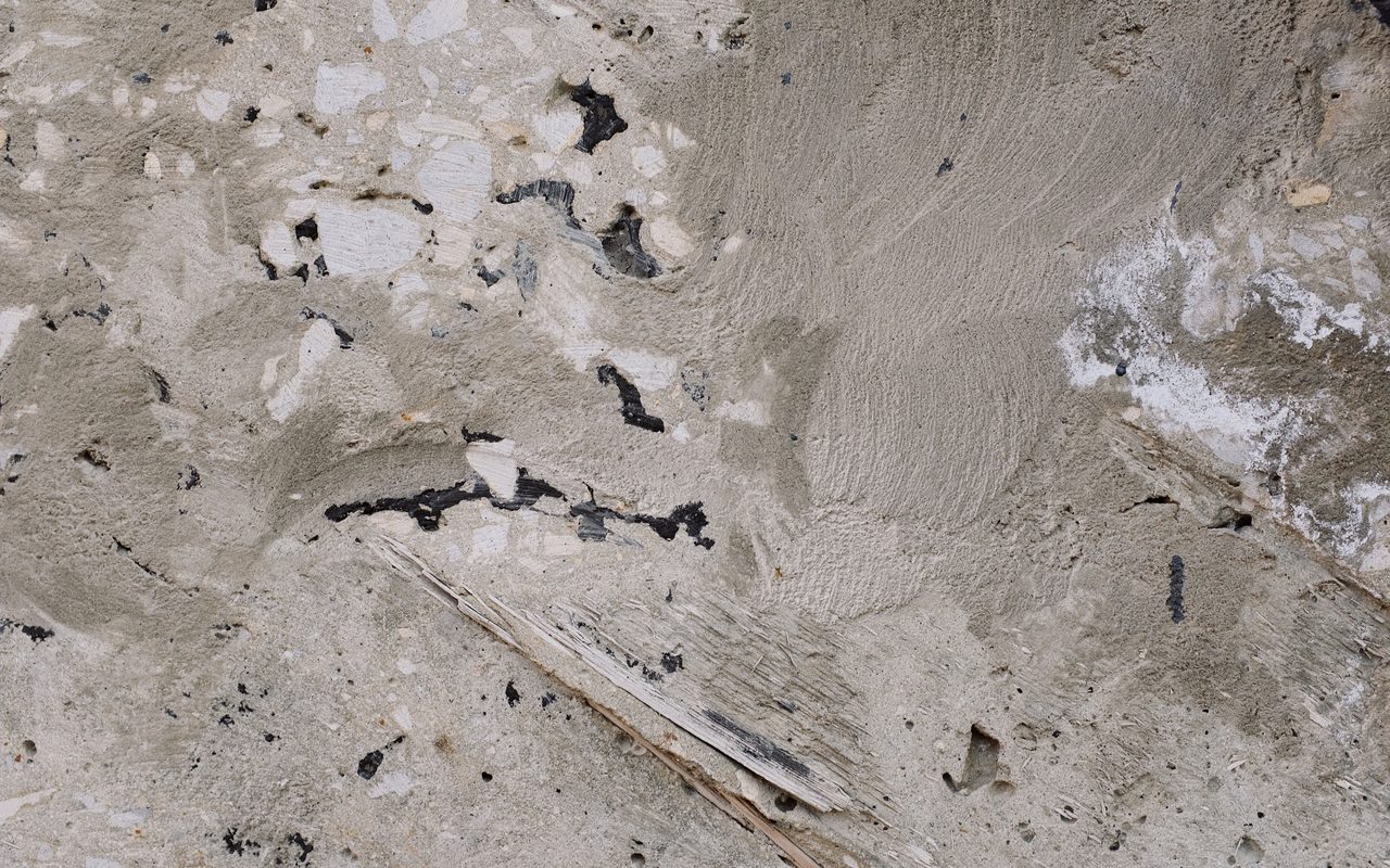 Worn concrete surface with patchy damaged areas and exposed aggregate